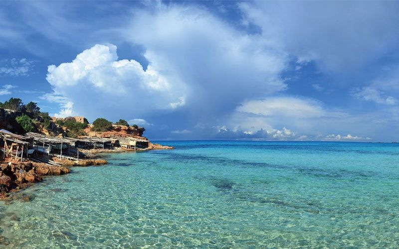 Aguas cristalinas en Ibiza con costa rocosa, cielo azul y horizonte mediterráneo: una imagen perfecta para inspirar calma y verano.